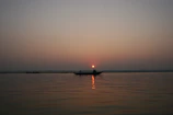 Couple sharing a quiet smile aboard a boat, framed by the glowing horizon and gentle waves.