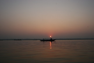 A serene sunset over a calm bay with a couple enjoying a private boat ride.