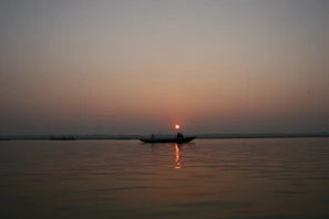 Couple sharing a quiet smile aboard a boat, framed by the glowing horizon and gentle waves.