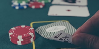 person holding black ace and king spades playing cards on poker table