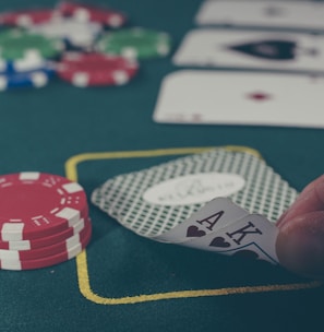 person holding black ace and king spades playing cards on poker table