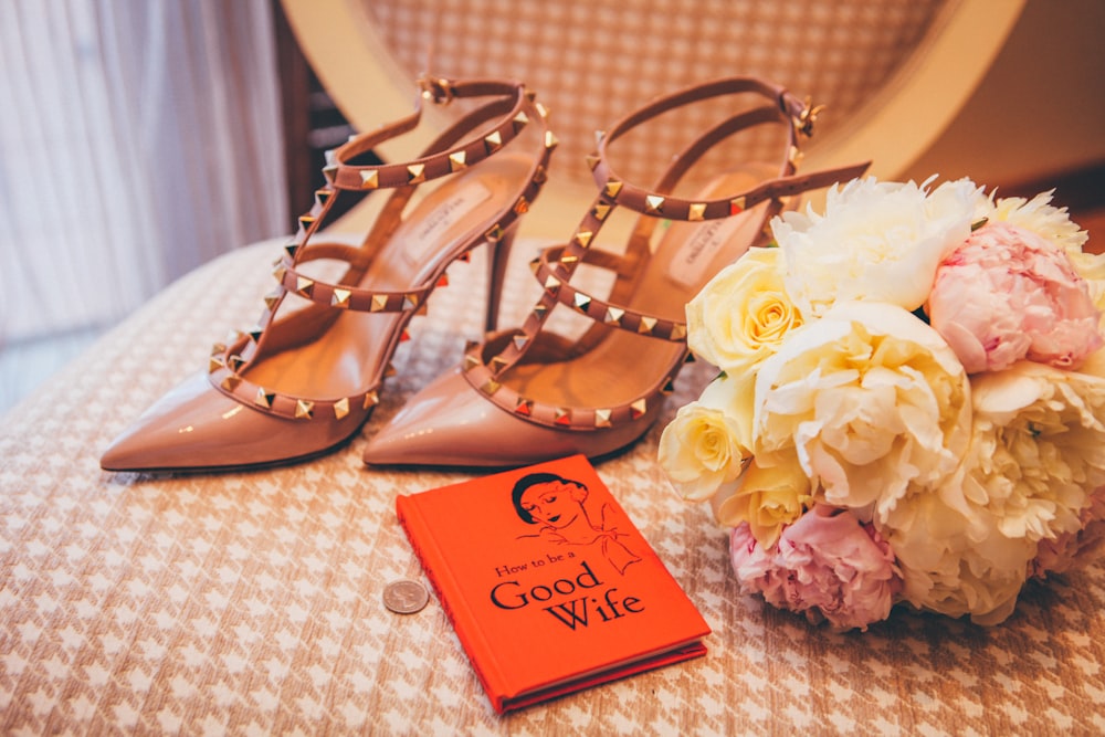 paire de sandales à talons pointus beiges près du bouquet de fleurs blanches et multicolores