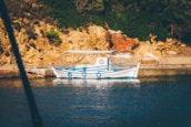 Aquamavi's service boat navigating calm blue waters near rocky shores.