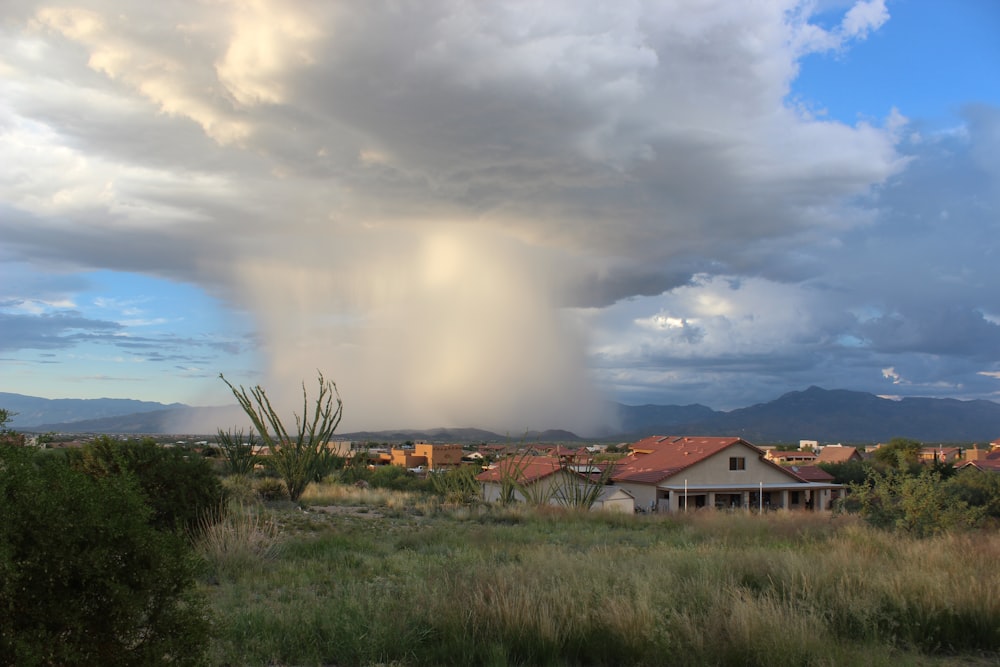 foto da formação de nuvens perto de casas durante o dia