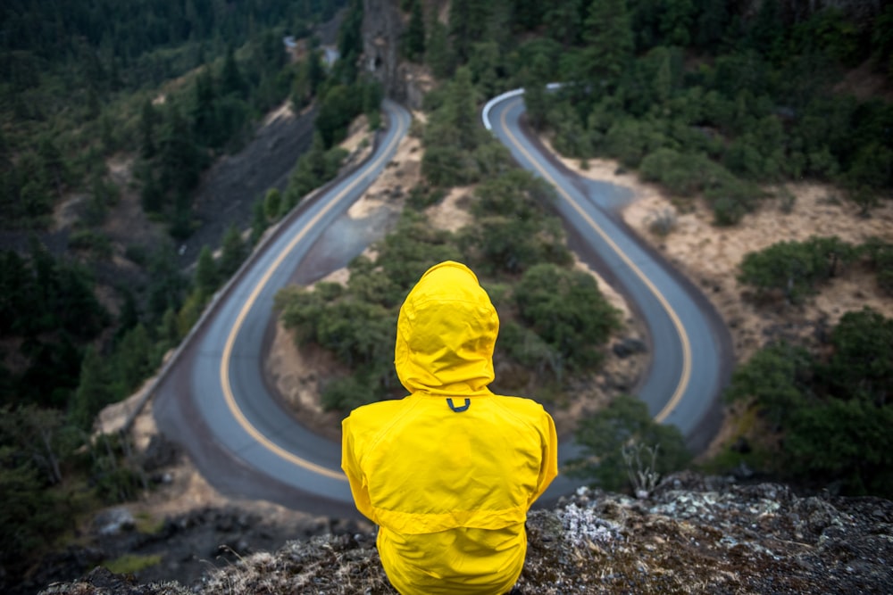 personne en manteau jaune debout au sommet de la colline