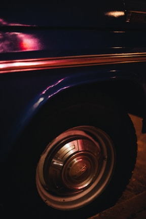 Close-up of a car fender with a flawless polished paint finish reflecting workshop lights.
