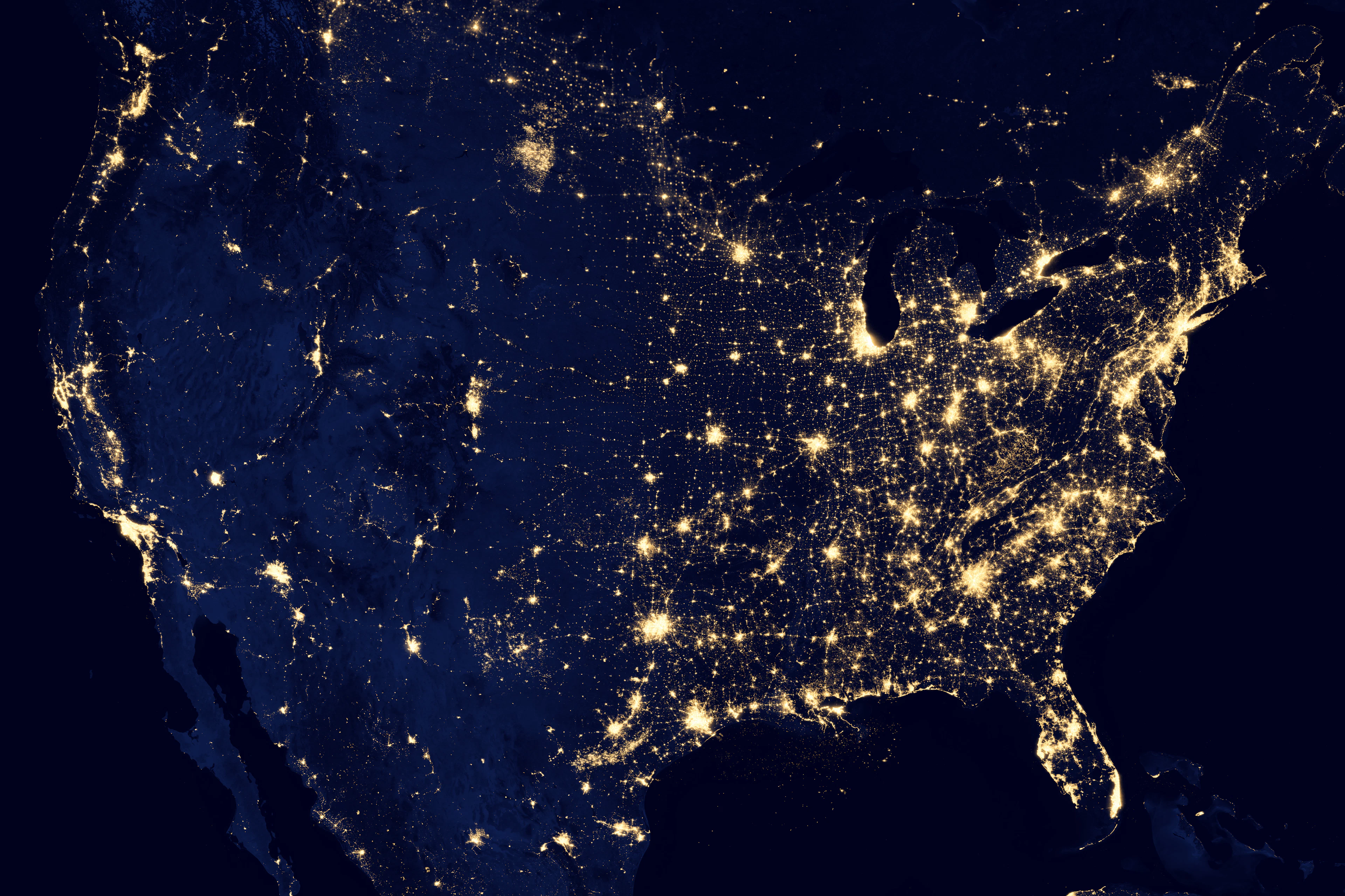 The United States at night seen from orbit, with city lights spread across the country