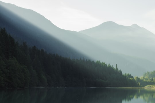 sunlight beaming from mountain top to body of water in Diablo Lake United States