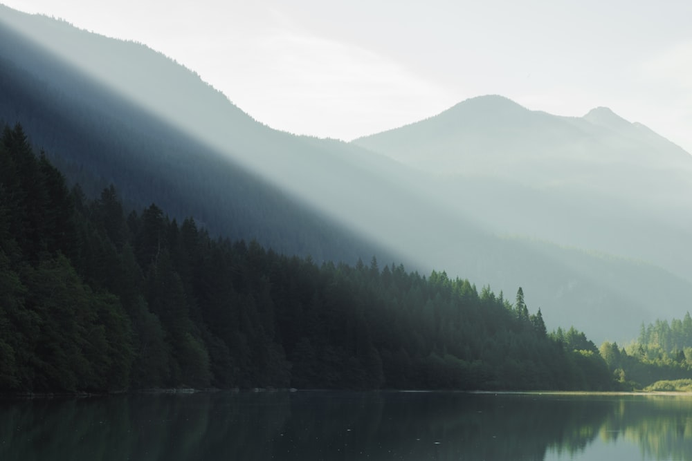 sunlight beaming from mountain top to body of water