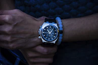 A stylish man wearing a Philipe Ricci watch in a casual setting, with a neutral beige background.