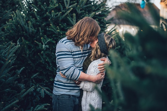 man kissing woman near pine tree in Nashville United States