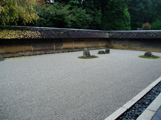 A minimalist Japanese-inspired garden with raked gravel and carefully placed stones.