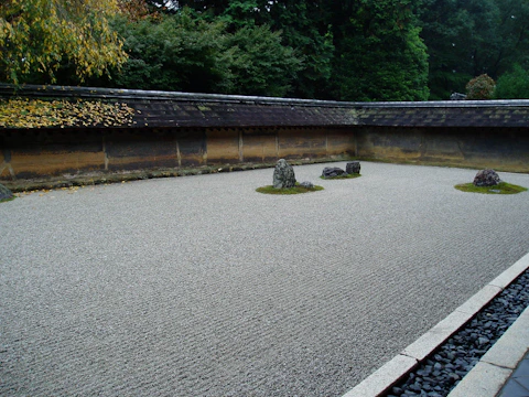 A minimalist Japanese-inspired garden with raked gravel and carefully placed stones.