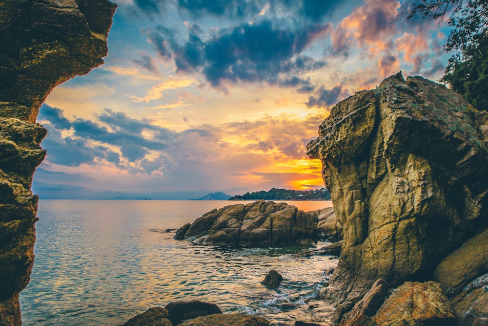 seashore near rocky mountain during golden hour