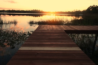 A technician installing a wooden dock by a serene lakeside at sunset
