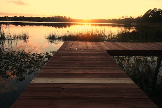 A technician installing a wooden dock by a serene lakeside at sunset