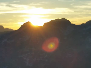 Copper droplet logo overlaying Andes mountain ridge at sunrise.