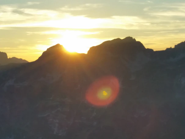 Copper droplet logo overlaying Andes mountain ridge at sunrise.