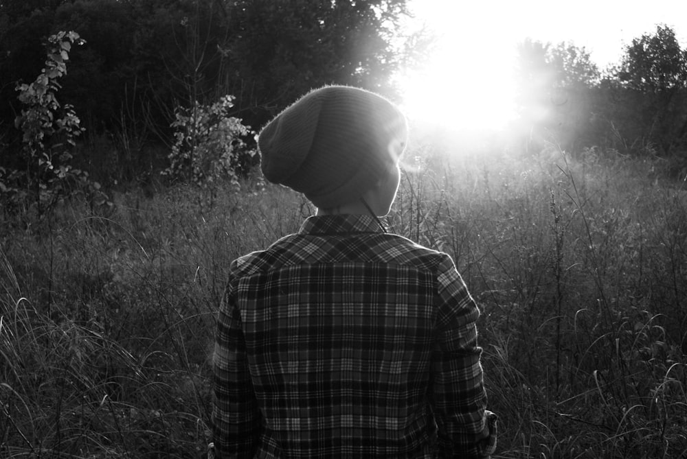 grayscale photo of person standing on grass field