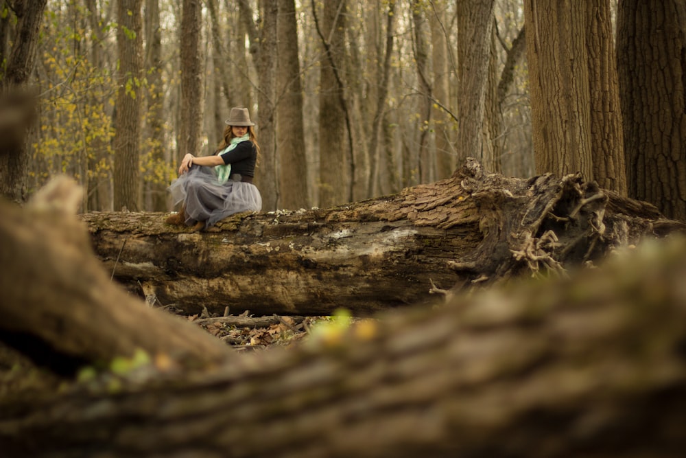 woman on top of brown tree log