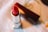 A red lipstick with a shiny silver casing is positioned on a soft, blurred background. The lipstick is partially extended, showing its vibrant color with a nearby closed cap.