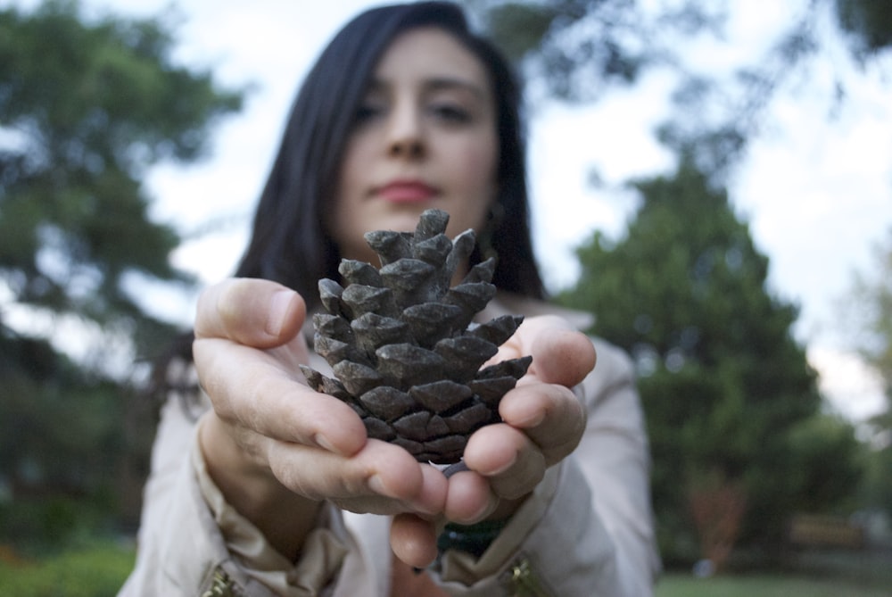 Fotografía de enfoque selectivo de mujer sosteniendo piña marrón