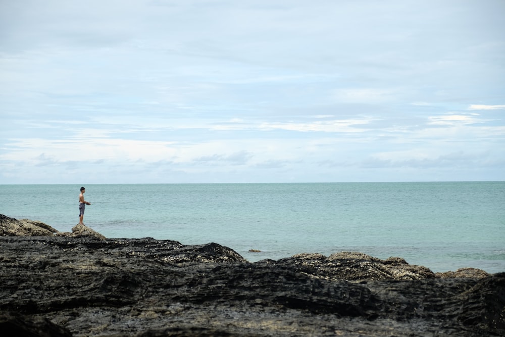 uomo in piedi sulla scogliera di fronte calmo specchio d'acqua