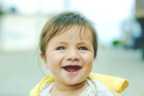A joyful child wearing a bright, handmade hair bow smiling outdoors