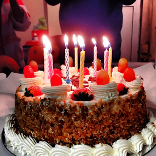 Close-up of a beautifully decorated birthday cake on a yacht deck with the sea and sunset in the background.