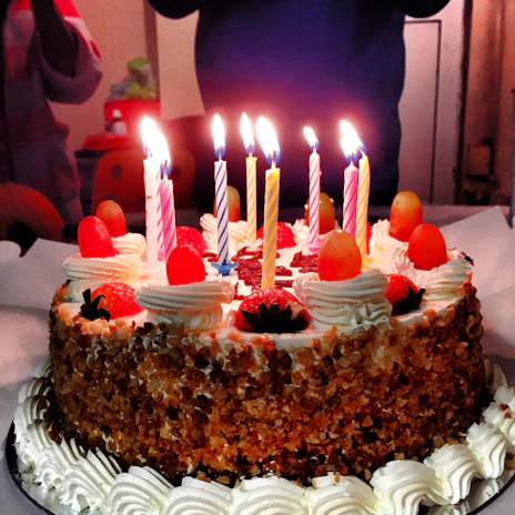 Close-up of a beautifully decorated birthday cake on a yacht deck with the sea and sunset in the background.