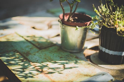 Close-up of a handcrafted metal planter with a green patina finish, resting on a beige surface.