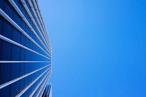 low-angle photography of curtain glass building under blue sky