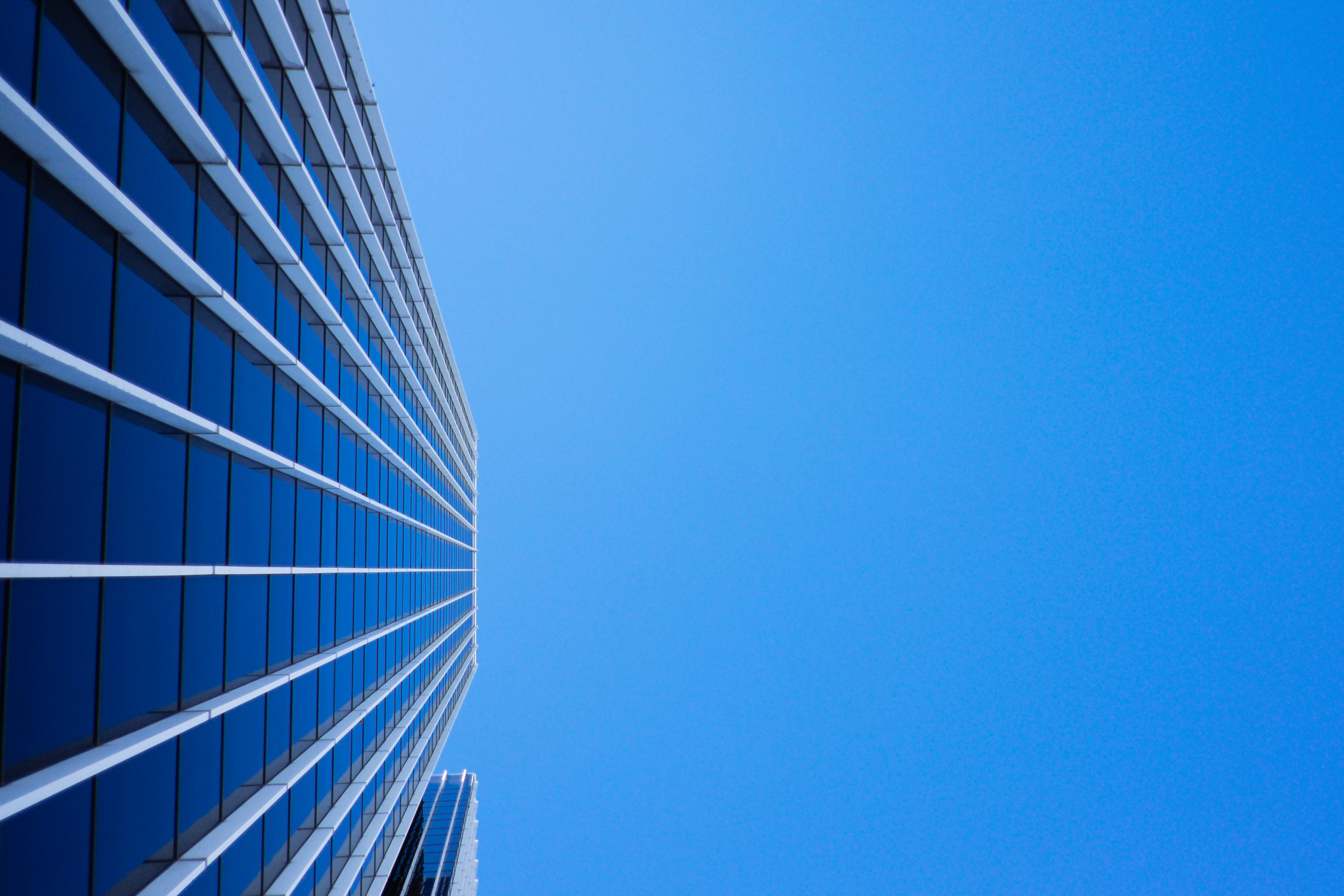 low-angle photography of curtain glass building under blue sky