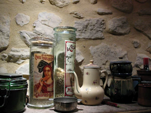 A rustic kitchen counter displaying jars of homemade jams, fresh milled flour bags, and a steaming cup of mushroom coffee.