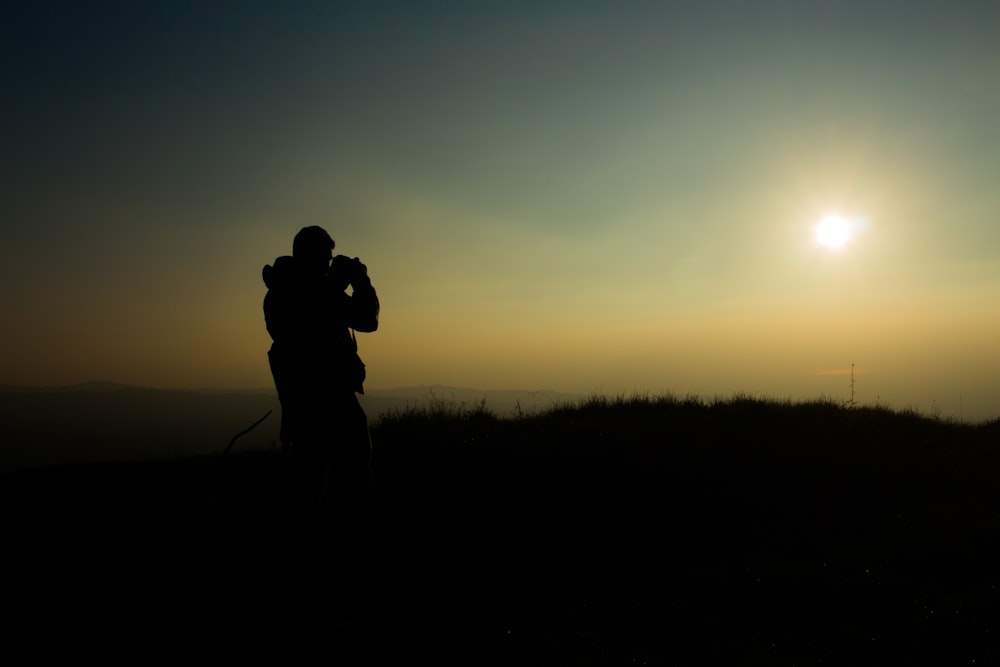 silhouette of man taking picture during golden hour