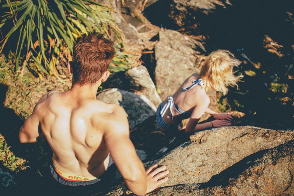 Couple in swimwear climbing down the rocky cliff at Kings Beach