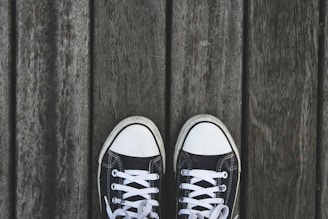 A pair of stylish men's sneakers displayed on a wooden surface.