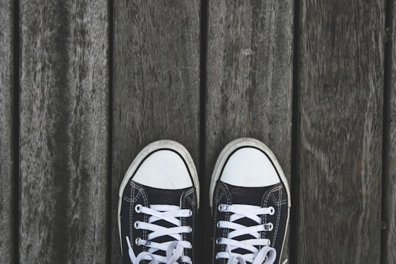 A pair of stylish men's sneakers displayed on a wooden surface.