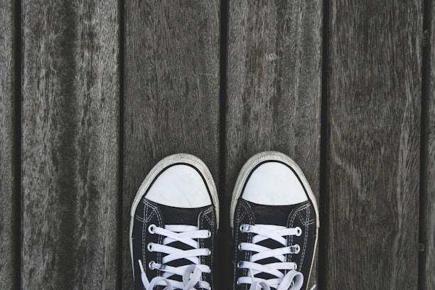 A pair of sleek black men's shoes on a wooden surface.