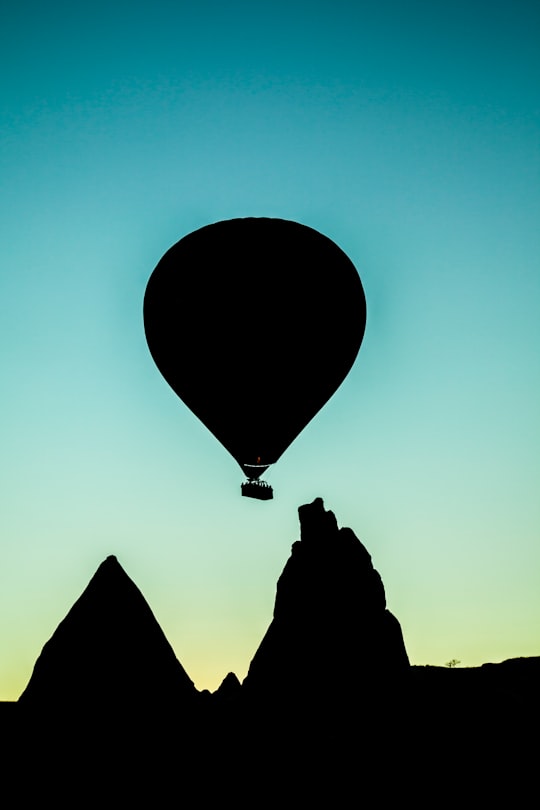 silhouette of hot air balloon flying above rock formation in Cappadocia Turkey