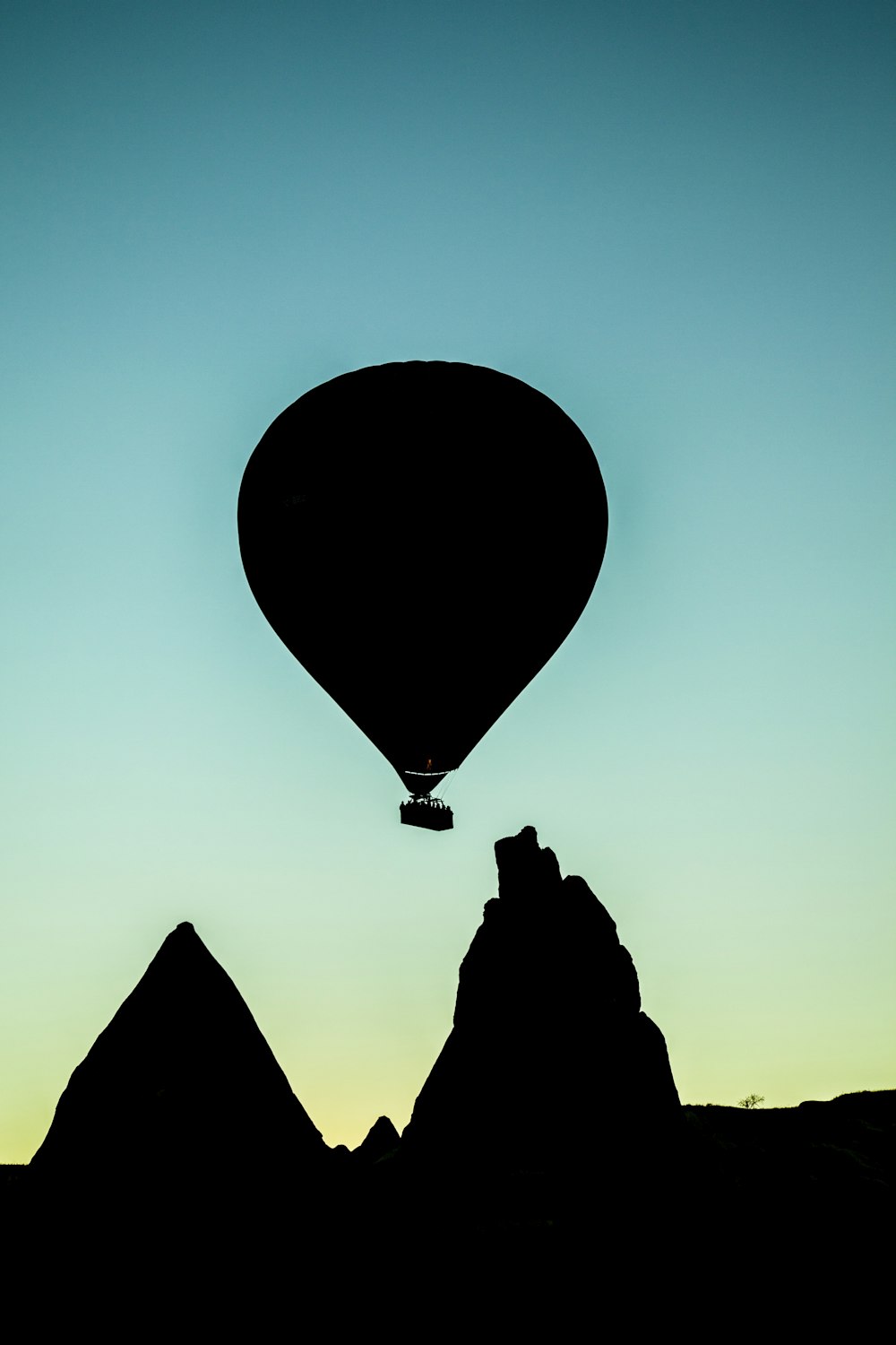 Silueta de globo aerostático volando sobre formación rocosa