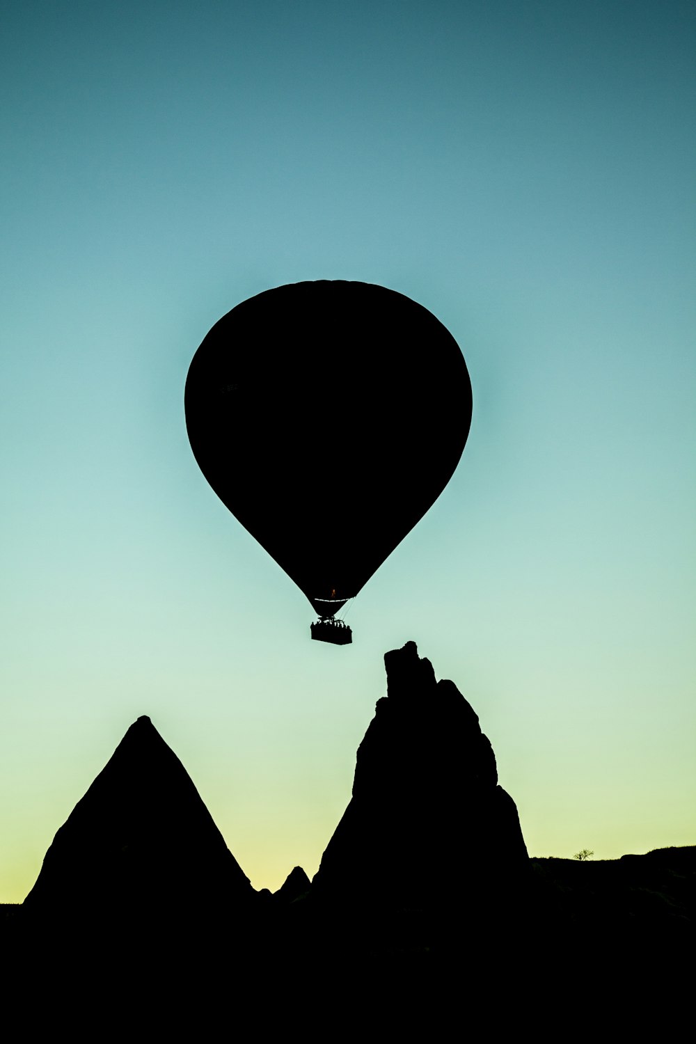 岩層の上を飛ぶ熱気球のシルエット