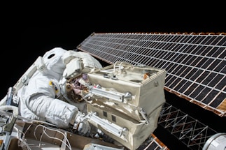 closeup photo of astronaut repairing satellite
