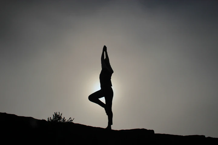 A figure holding tree pose at sunrise