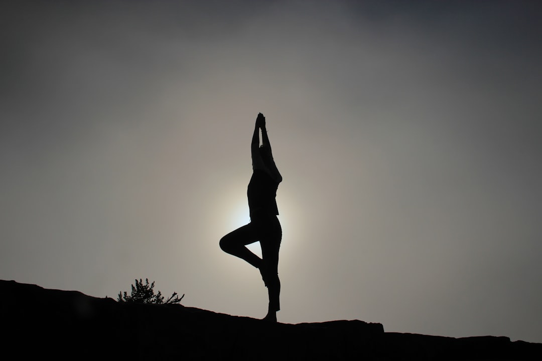 A person doing yoga on a sloping ground in silhouette
