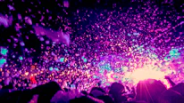 Brightly lit disco dome bouncy castle with kids dancing and foam filling the air.