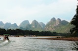 Peaceful river scene in Laos with wooden boats and misty mountains.