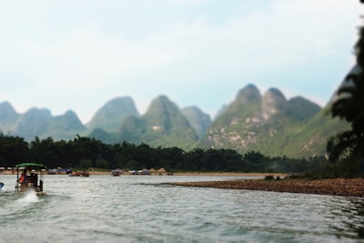 Peaceful river scene in Laos with wooden boats and misty mountains.