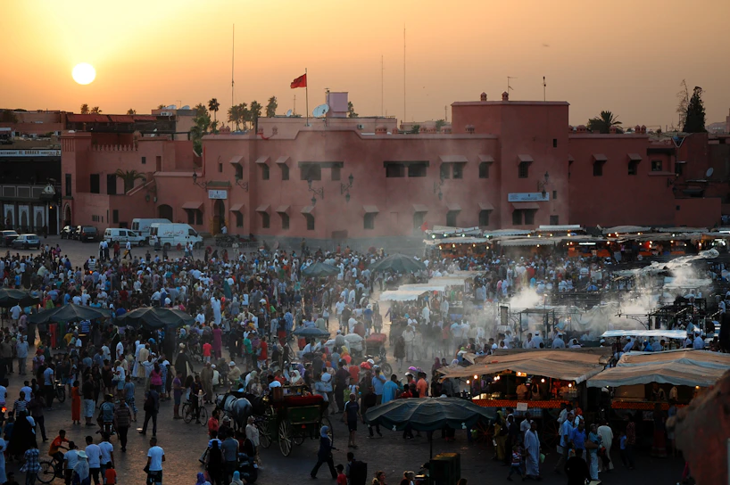 A vibrant crowd gathered at a bustling street market in India during sunset.