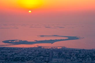 Aerial view of Dubai’s coastline with oil tankers anchored near the shore at sunset.